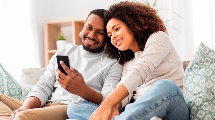casal utilizando telefone e sorrindo