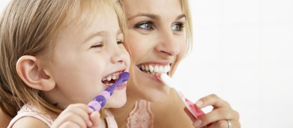 Mãe e filha escovando os dentes juntas
