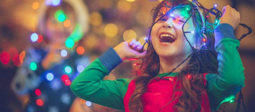 Criança brincando com pisca pisca de natal
