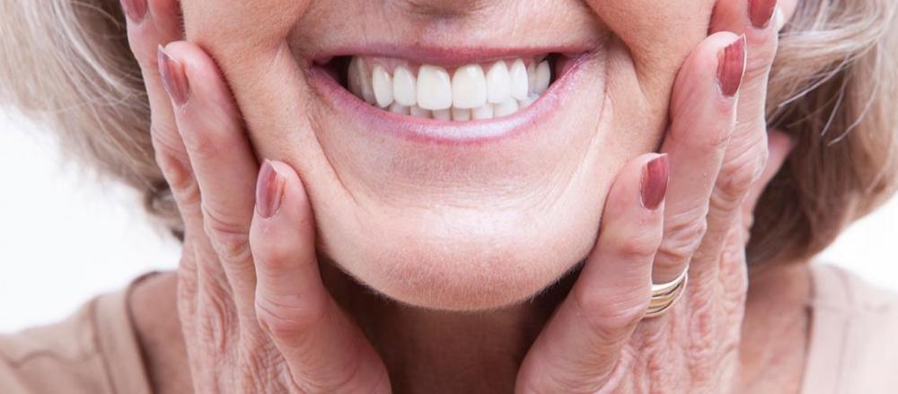 Mulher sorrindo, com as mãos na bochecha