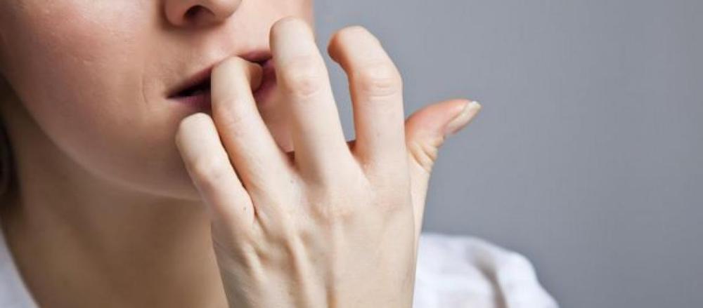 Pessoa roendo unhas das mãos