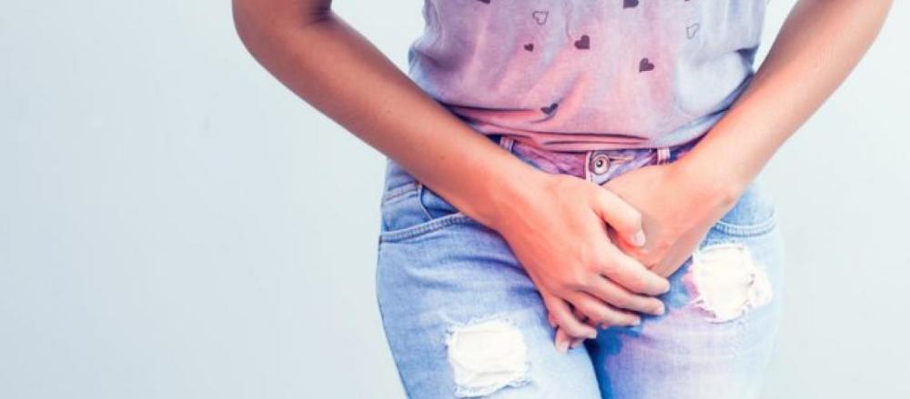 Mulher cobrindo as partes intímas por cima da roupa, dinicando dores