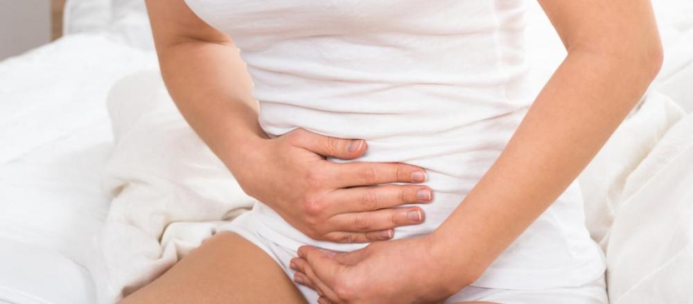 Mulher levando as mãos a barriga, indicando dores