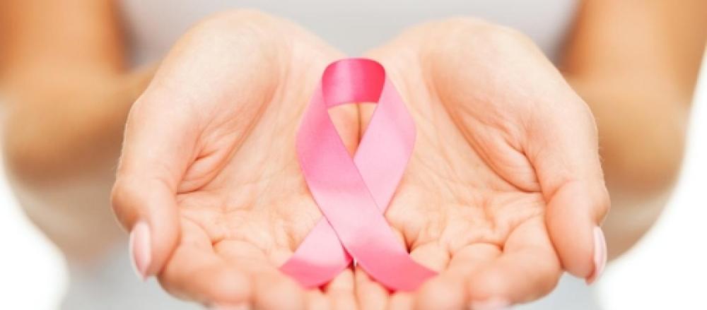 Mãos femininas em destaque, segurando uma fita rosa, em alusão ao outrubro rosa