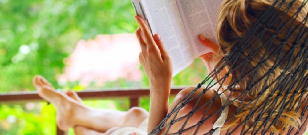 Mulher lendo livro deitada na rede