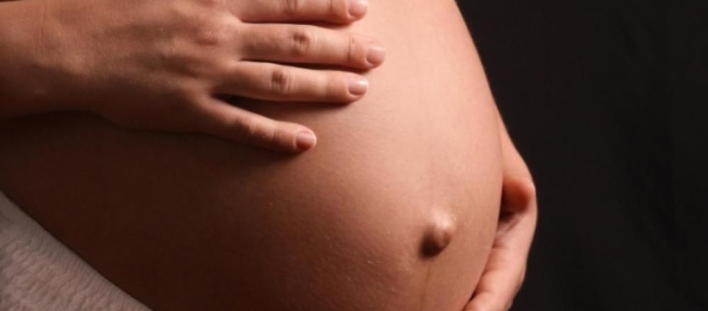 Mulher grávida segurando a barriga com as mãos