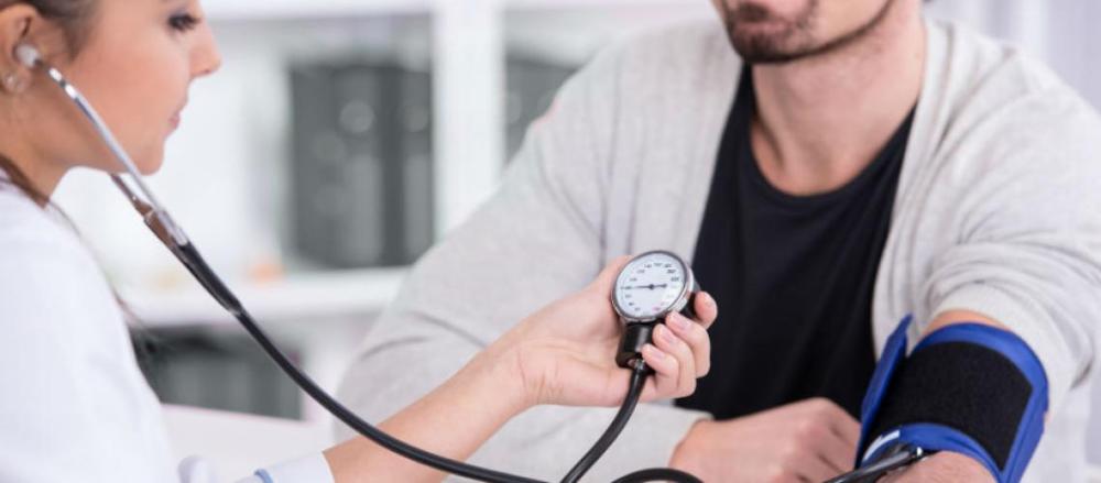 Homem aferindo pressão arterial em consulta médica