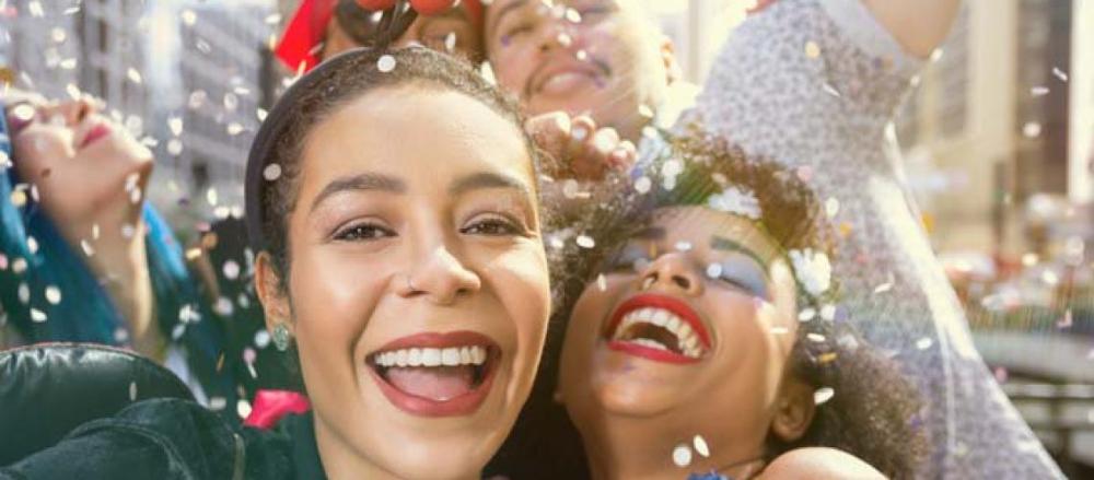 5 pessoas curtindo o carnaval, com chuva de confetes coloridos