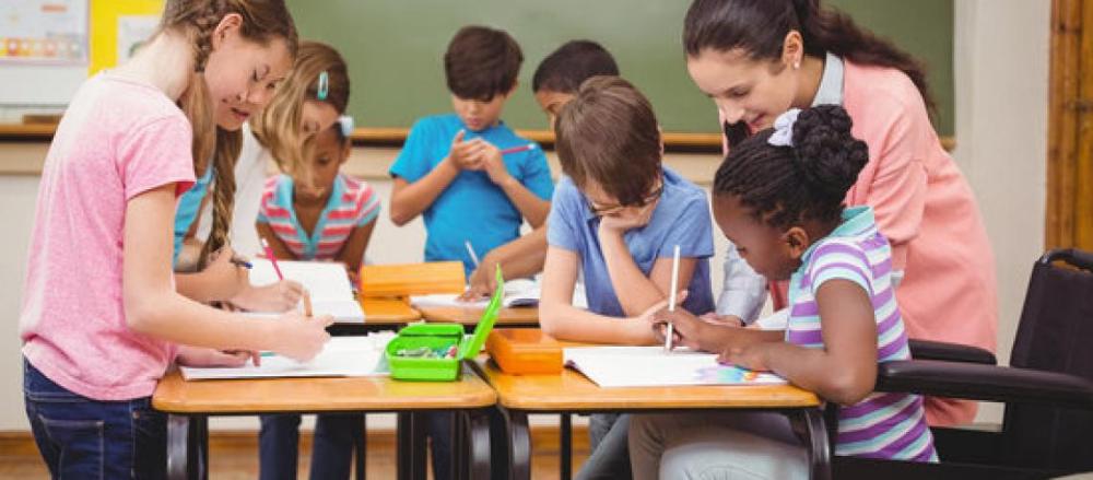 Ambiente de sala de aula com uma professora ajudando as crianças com as tarefas