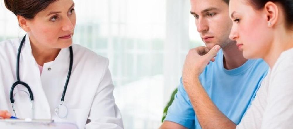 Casal com expressão série, em consulta com médica