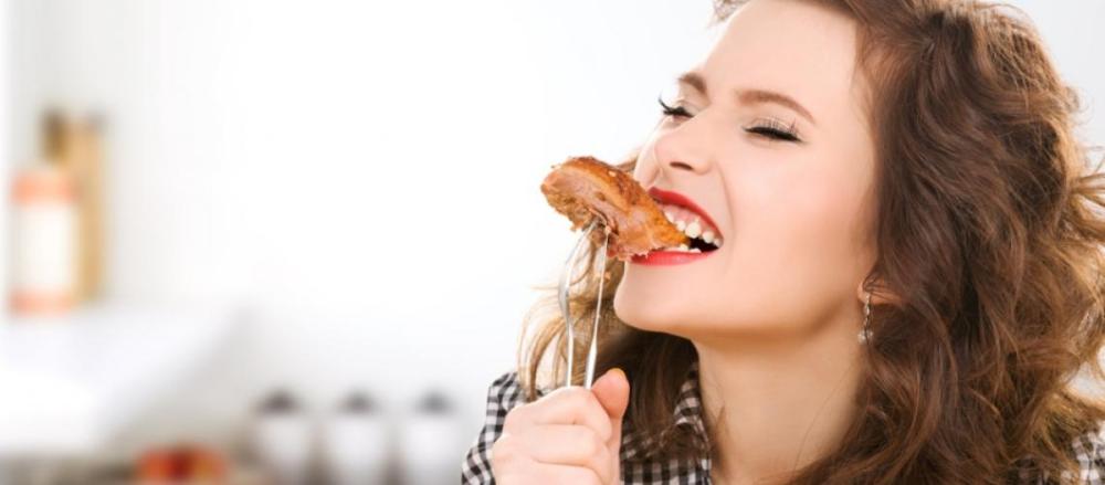 Mulher comendo um pedaço de carne