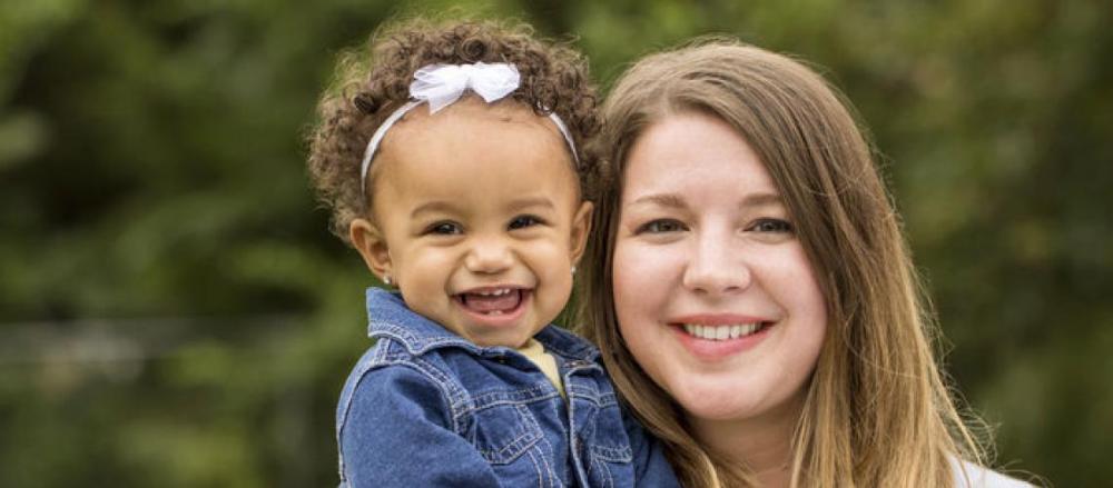 Mãe sorridente com filha no colo