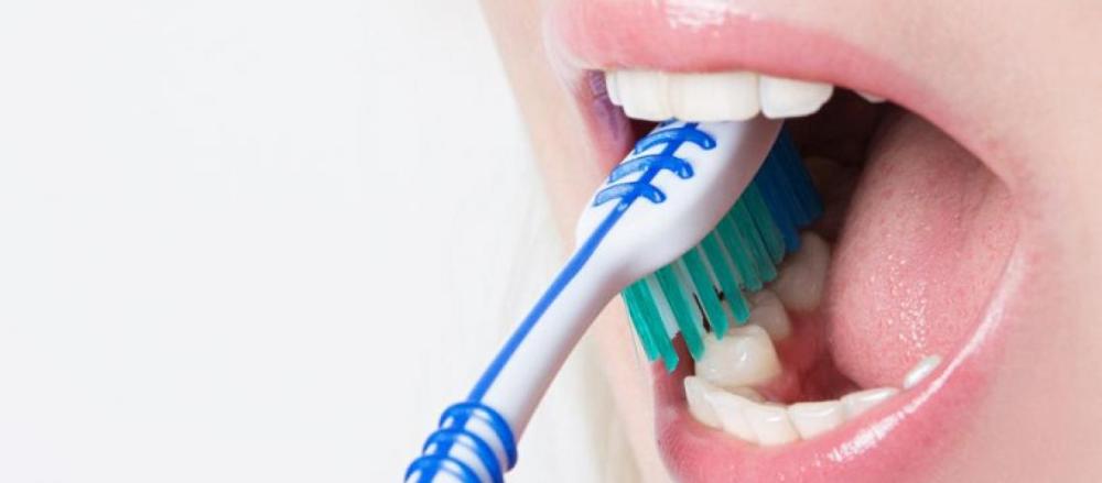 Pessoa com escova de dentes na boca