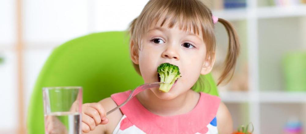 Criança comendo um brócolis
