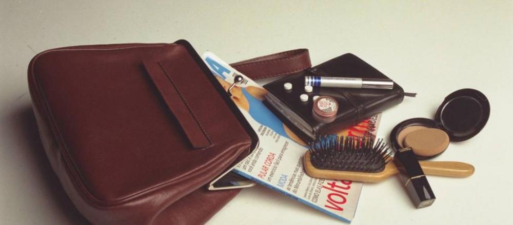 Uma bolsa com algusn itens como uma revista e maquiagens