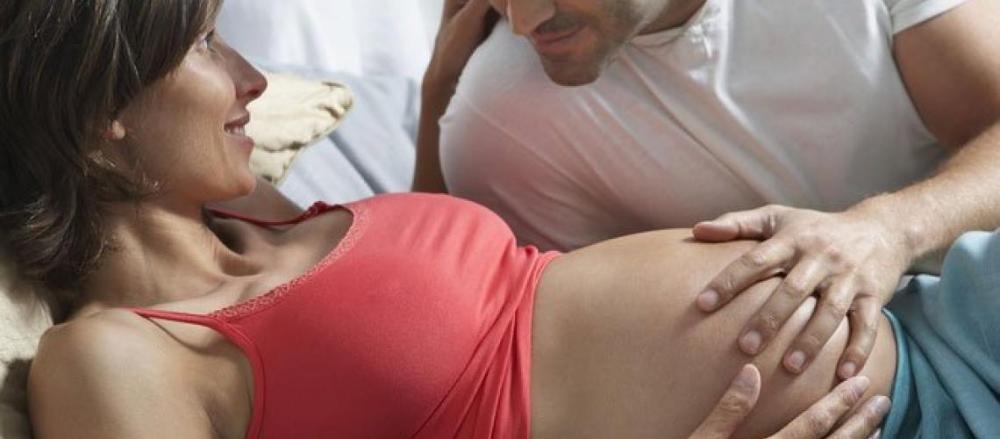 Mulher grávida e parceiro acariciando sua barriga