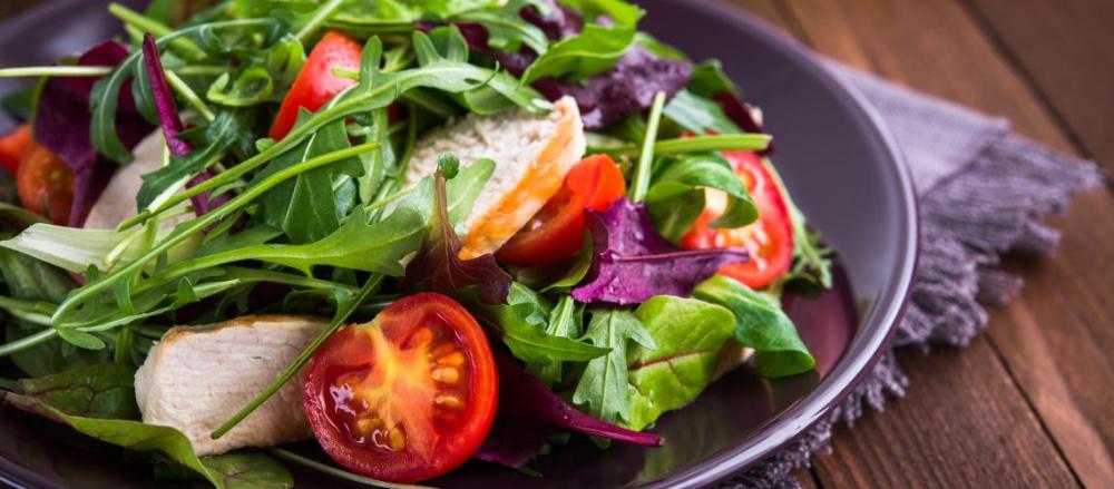 um prato de salada encima de uma mesa de madeira