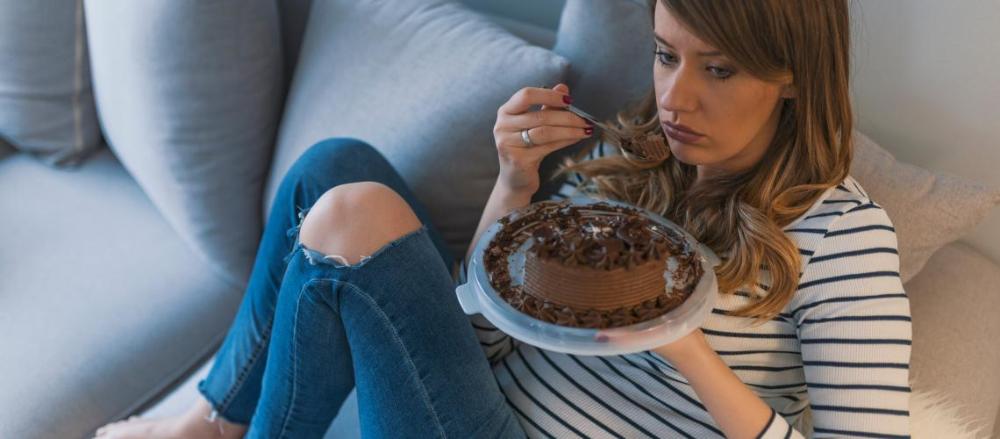 Mulher comendo bolo no sofá