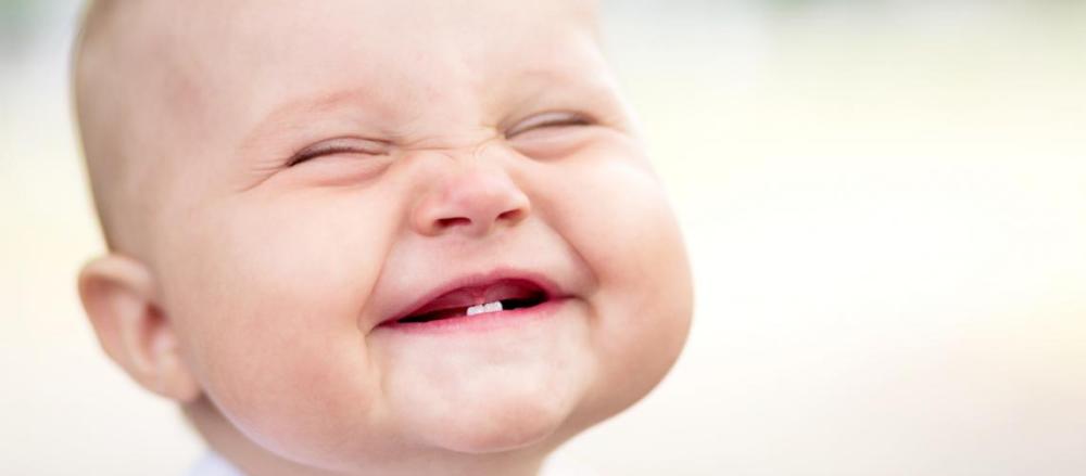 Bebê sorrindo com dois dentes visíveis