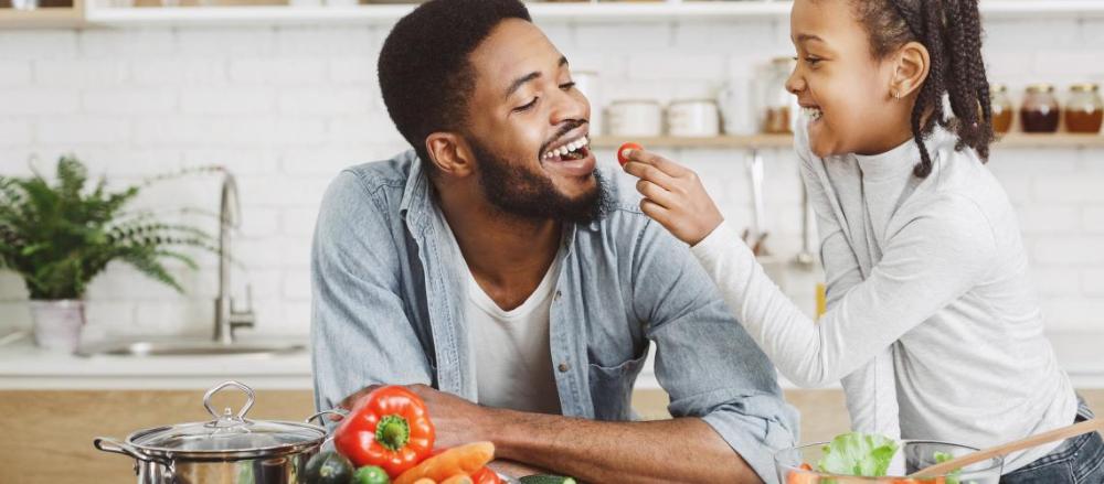 Criança dando comida na boca do pai com as mãos