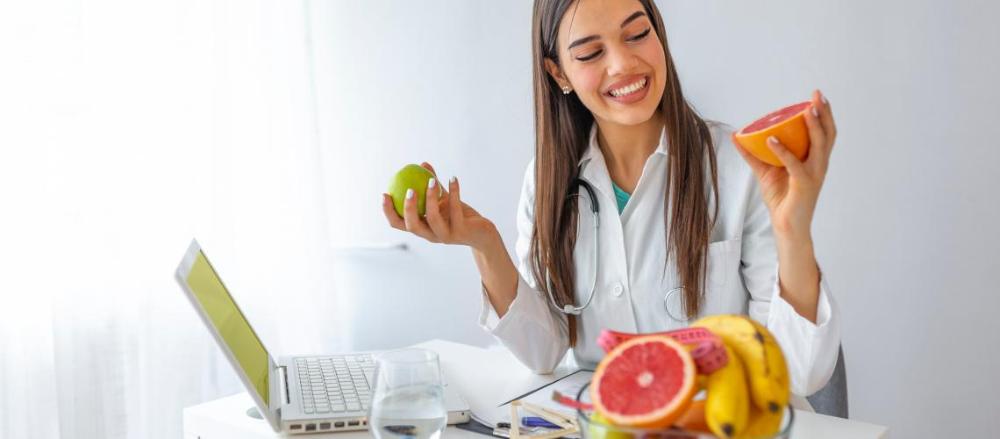 Nutricionista sorrindo ao segurar algumas frutas