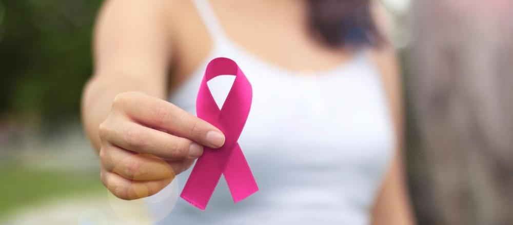 Uma mulher segurando uma fita rosa, em alusão ao outubro rosa