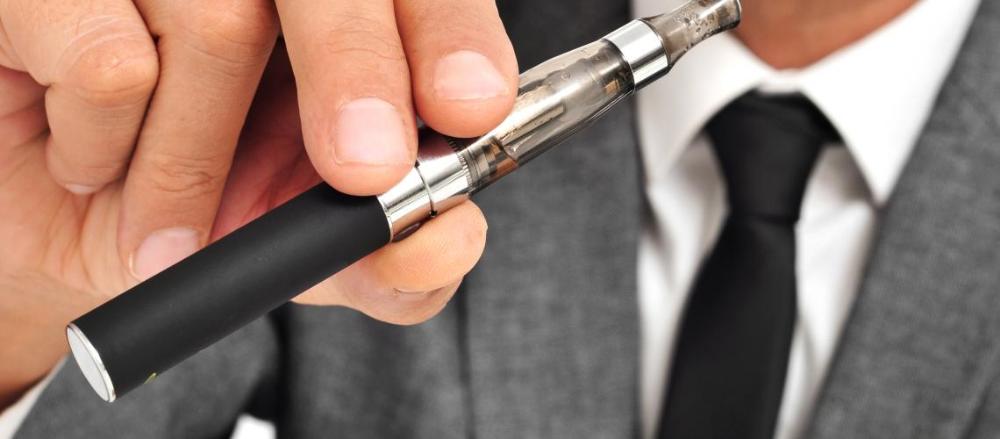 Homem de terno segurando cigarro eletrônico
