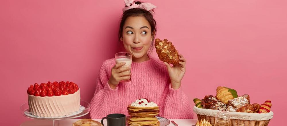 Mulher feliz com vários doces ao redor