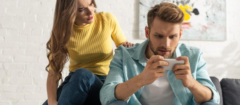 Homem concentrado no celular e mulher insatisfeita com a situação