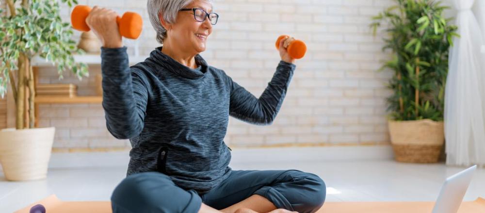 Mulher idosa fazendo exercícios sentada no chão