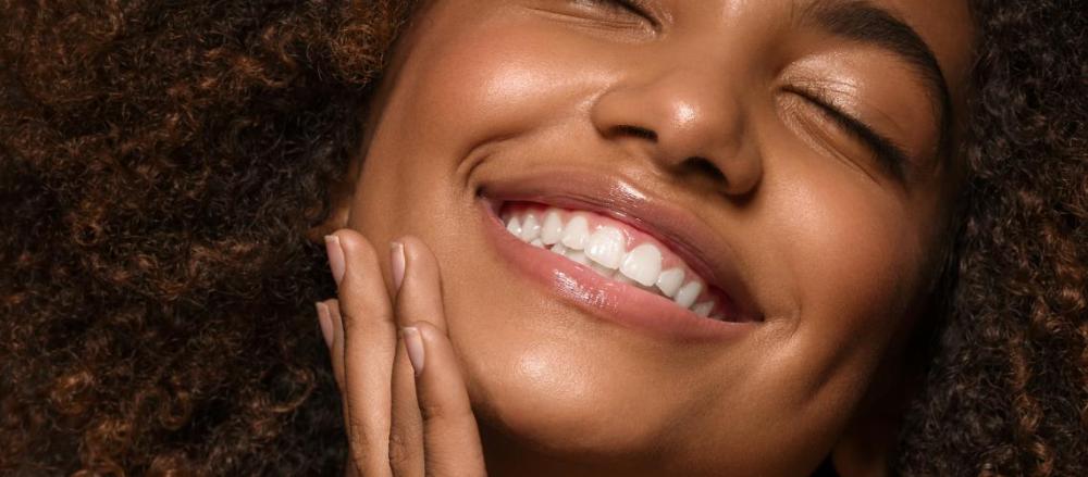 Mulher sorrindo de olhos fechados expressando plenitude