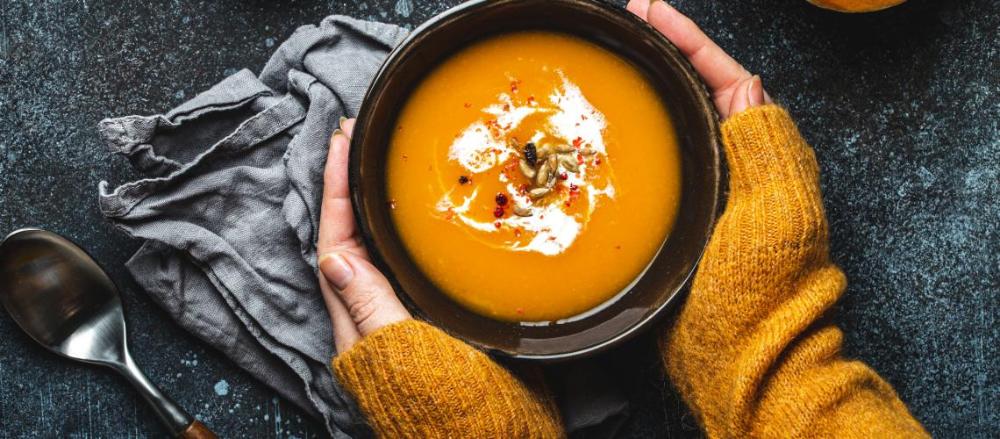 Close de uma mão segurando uma tigela de sopa