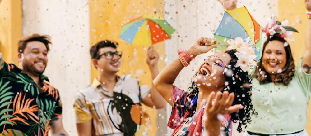 4 pessoas curtindo o carnaval, com chuva de confetes coloridos