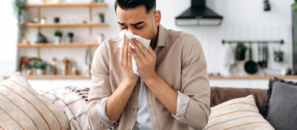Homem resfriado sentado n osofá