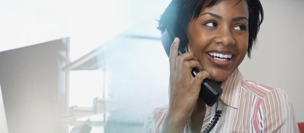 Mulher sorrindo enquanto usa o telefone em ambiente corporativo