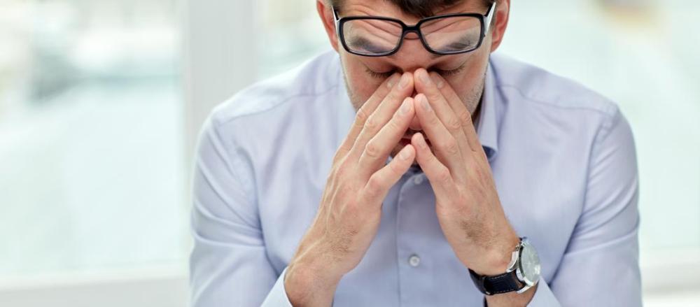 Homem com as mãos no rosto e expressão estressada