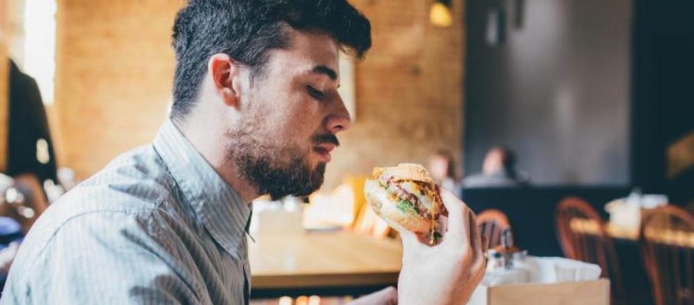 Homem comendo hambúrguer