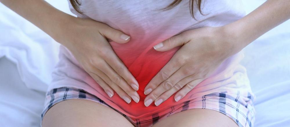 Mulher levando a mão a barriga, com destaque avermelhado, indicando dores