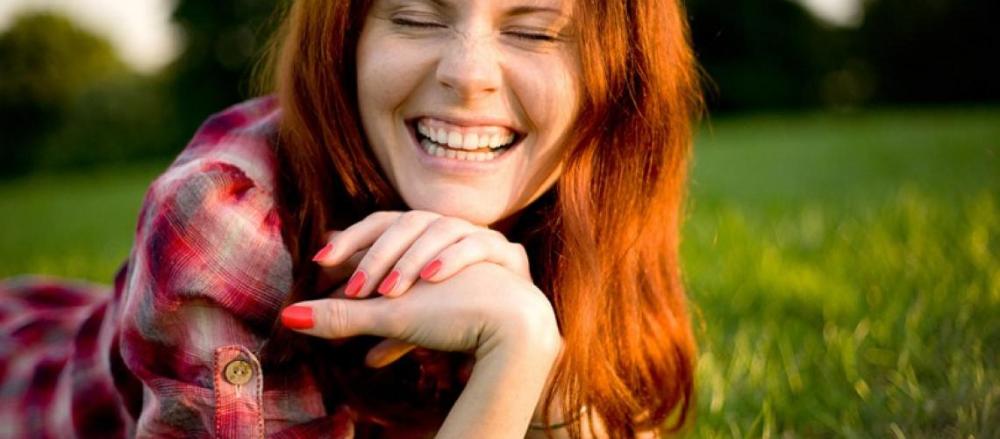 Mulher sorridente ao ar livre, de olhos fechados