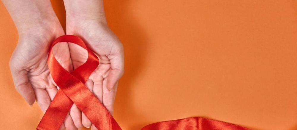 Pessoa segurando fita laranja, e alusão ao dezembro laranja