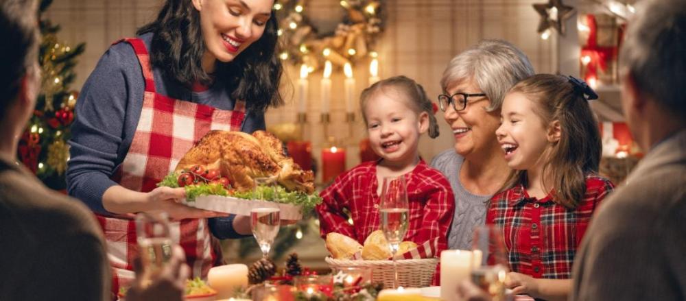 Mulher levando frango assado a mesa, em provável ceia de natal