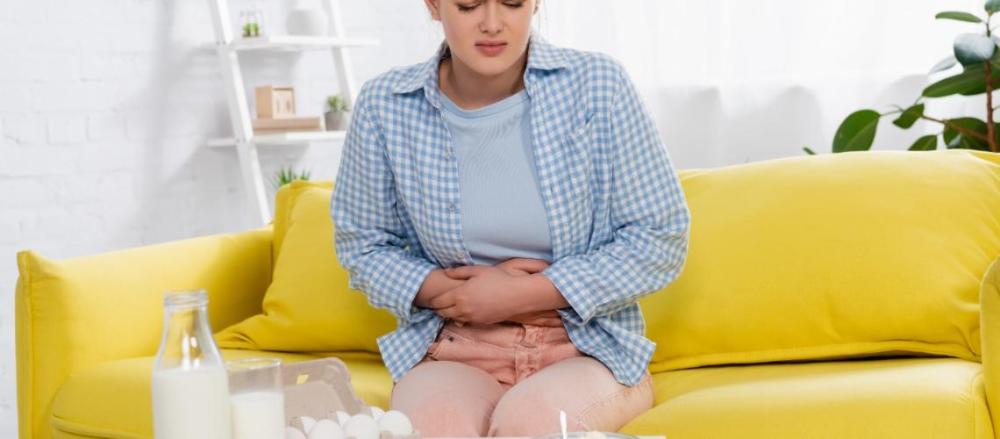 Mulher com expressão de dor, segurando as mãos sobre a barriga