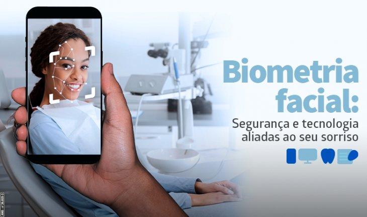 Imagem de uma mulher em uma consulta odontológica, com u celular apontado para seu rosto e a frase Biometria facial: segurança e tecnologia aliadas ao seu sorriso