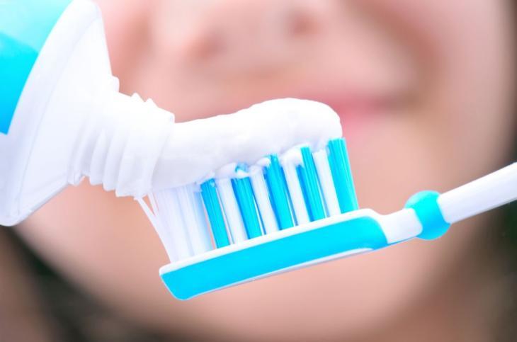 Imagem de um creme dental sendo aplicado em uma escova de dentes, destacando seus componentes