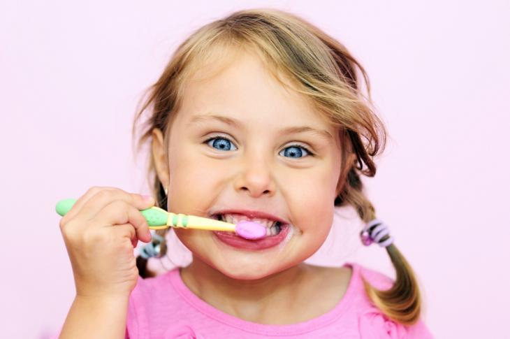 Imagem de menina sorrindo escovando os dentes, indicando que a escovação dos filhos pode ser criativa
