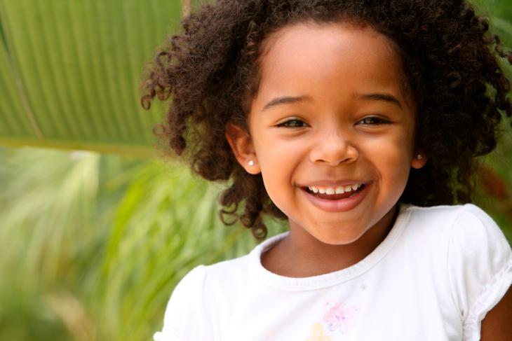 Imagem de uma criança sorrindo com dentes de leite, representando o desenvolvimento da dentição e troca para dentes permanentes