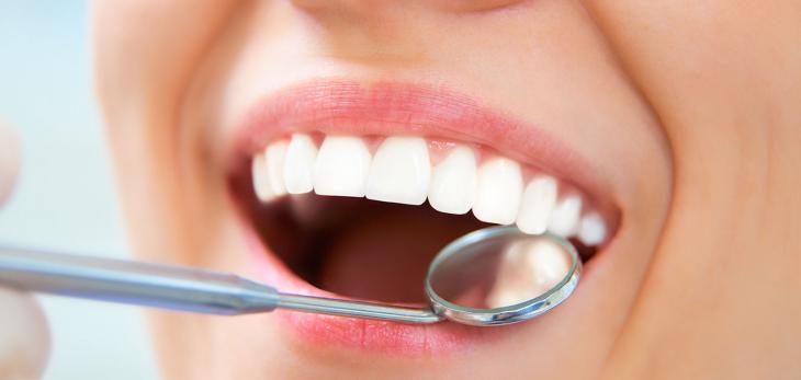 Imagem de uma mulher sorrindo em consulta odontológica, simbolizando a prevenção das gengivas inflamadas