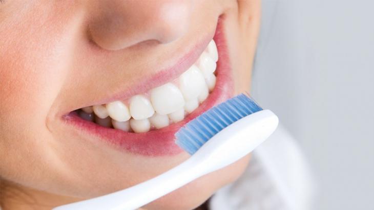 Imagem de uma mulher escovando os dentes, destacando a importância da saúde bucal, no sangramento gengival