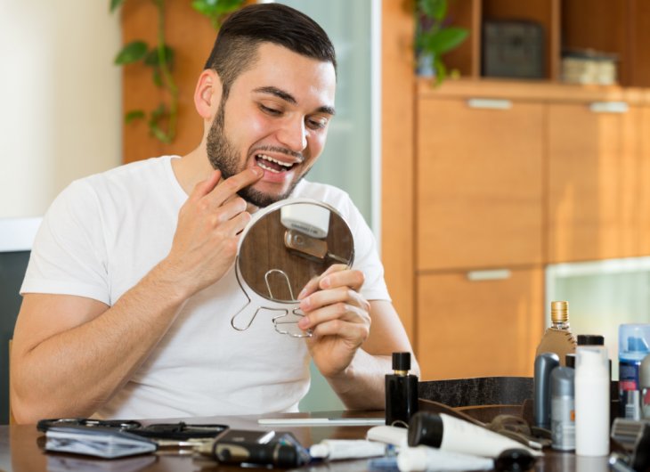 Homem olhando seus dentes em um espelho, representando tipos de manchas nos dentes