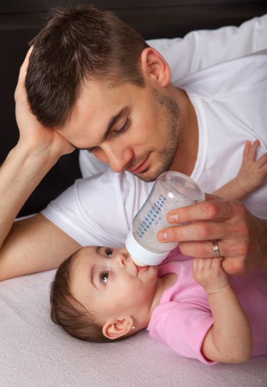 Imagem de um pai amamentando sua filha com mamadeira, reforçando a necessidade de cuidados para evitar a cárie de mamadeira